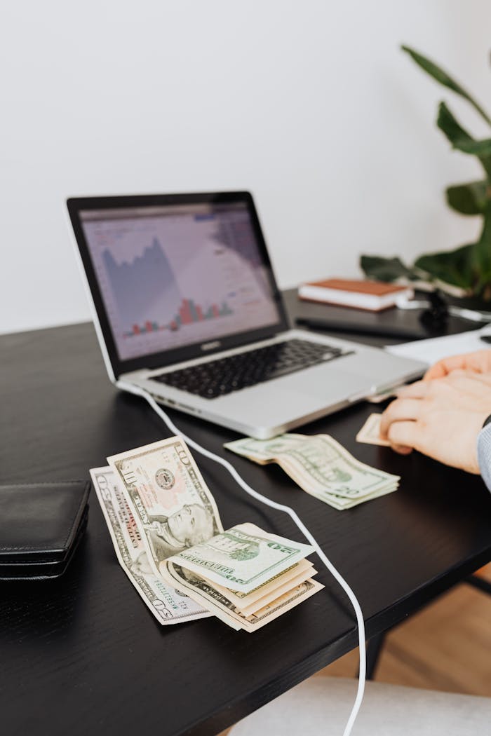 who-we-are Money and laptop on desk indicating financial work or analysis. Perfect for business themes.