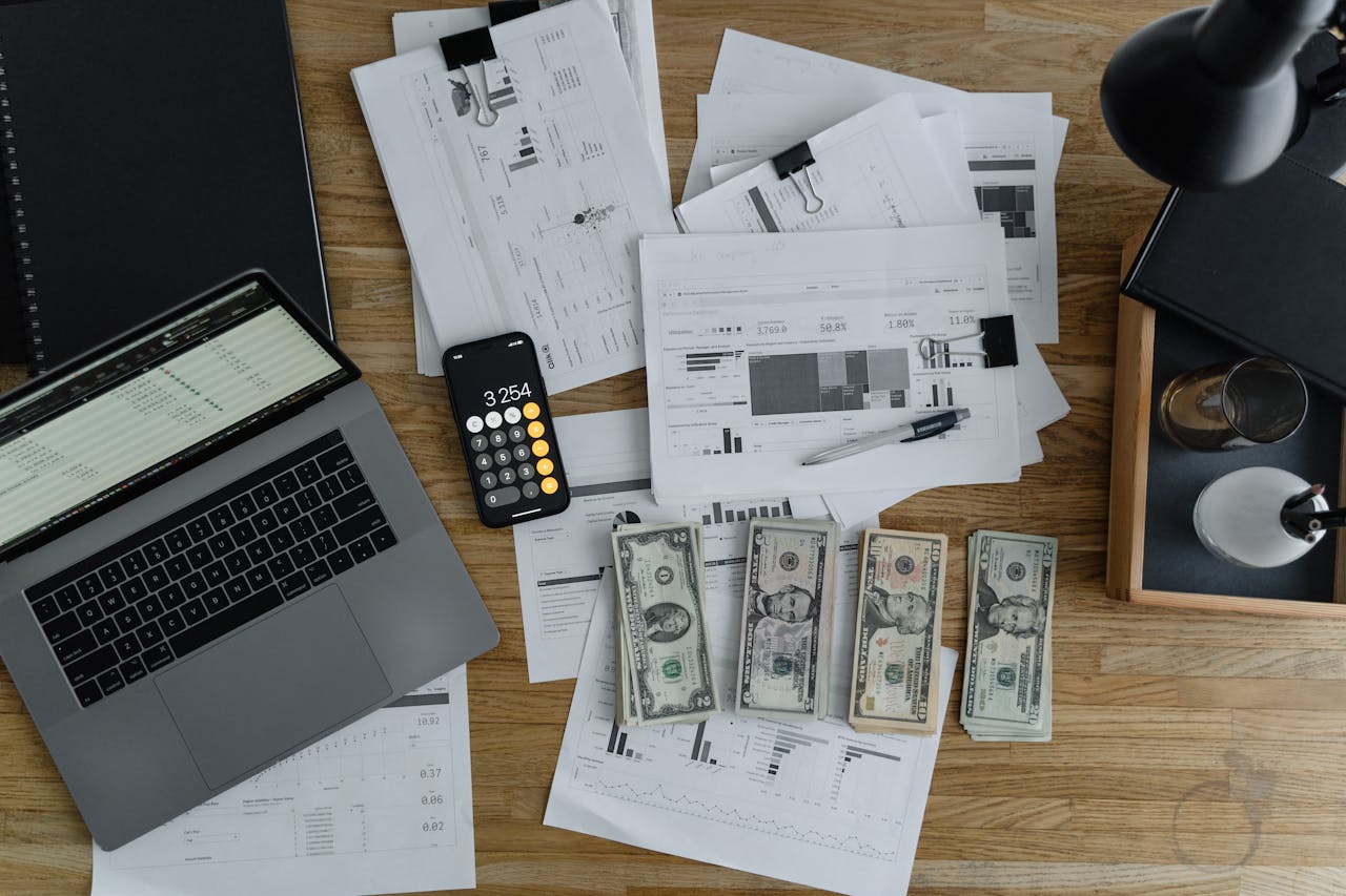 services-03 Overhead view of financial documents, cash, and technology on a wooden desk.
